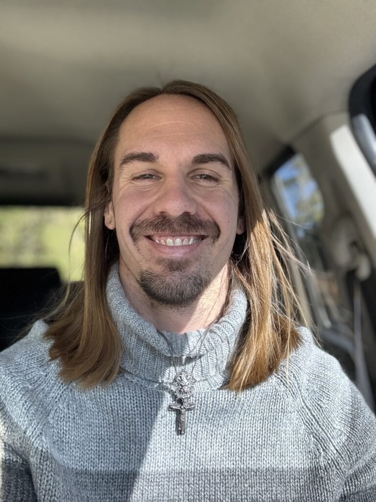 Me sitting in my car with a cross around my neck.